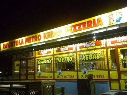 Metro Kebab Ulvilan julkisivu iltavalaistuksessa: valaistu keltainen kyltti ja Coca-Cola-reuna.